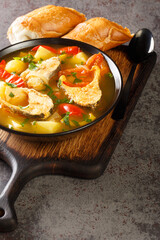 Caldeirada de peixe Portuguese fish stew with potatoes, peppers, tomatoes and onions close-up in a bowl on the table. Vertical