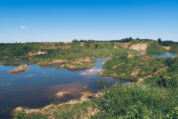 Fototapeta na wymiar Flooded sand quarry near Sychevo area. Lush green summer landscape for outdoors vacation, hiking, camping or tourism. Volokolamsk district of Moscow region. Russia