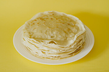 Thin pancakes are a national Russian dish. Fresh dish on yellow background