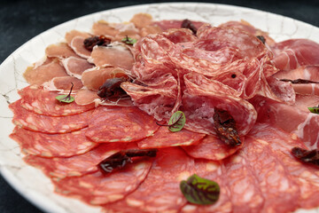 Sliced meat on a white plate, on a dark background