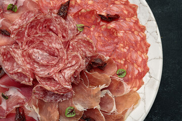 Sliced meat on a white plate, on a dark background