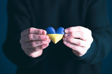 Heart flag of Ukraine in human hands. No war, peace for Ukraine concept.