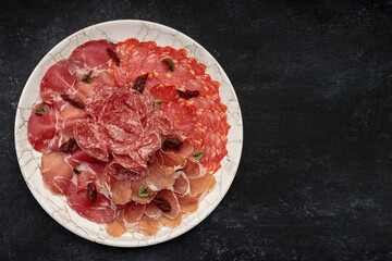 Sliced meat on a white plate, on a dark background