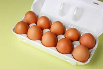 Brown eggs in expanded polystyrene packaging on an isolated light yellow background