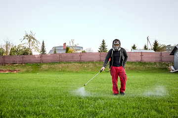 Farmers spraying pesticide on lawn field wearing protective clothing. Insecticide sprayer with a...