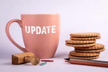 Update, business concept. Coffee mug, cookies and office supplies on a white background