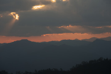 Fototapeta premium Sun rays over mountain range silhouette in an evening