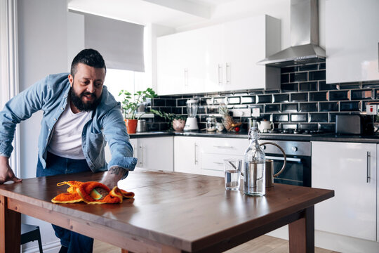 Man cleaning kitchen island with cloth in kitchen at home
