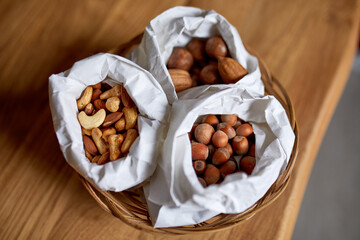 Top view Various sort of nuts on the table in a paper bag on wooden background, shopping grocery concept,  nuts delivary,  Zero Waste Food Shopping. Copy space..