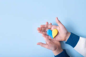 Heart of yellow-blue colors of the national flag of Ukraine in a childs hands, top view