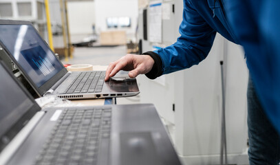Hand of technician using laptop in factory