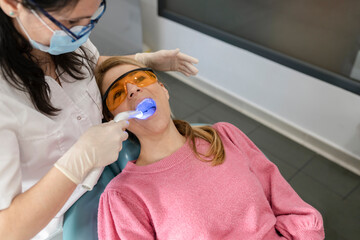 Dentist drying dental filling with curing light at dental clinic