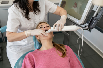Dentist using dental camera for scanning teeth of patient at dental clinic