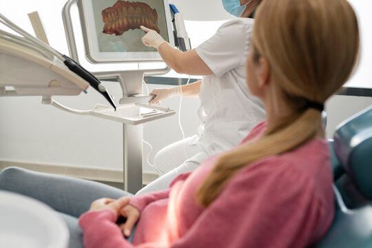 Dentist explaining teeth image on computer screen to patient in dental clinic