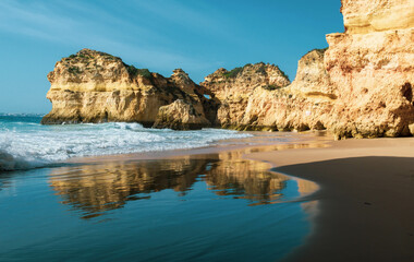 Dramatic coastline and beach in the Algarve region of Portugal with the landscape reflected in the...