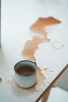 Spilled cup of coffee on table at home