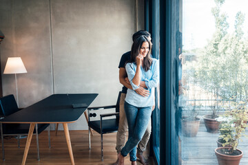 Smiling woman standing with boyfriend by glass window at home