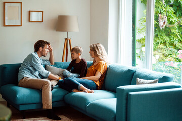 Man and woman sitting with son on sofa in living room at home