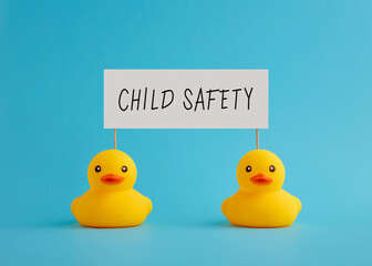 Two rubber ducks carry a signboard with the message child safety.
