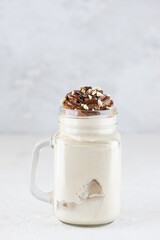 Coconut milkshake with chocolate and nuts on a light background.