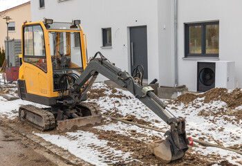 Kleiner Bagger abgestellt vor einem Neubau