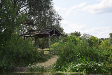 A wooden gazebo near the river bank, against the backdrop of the chalk mountains.