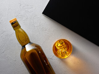 Glass of elegant whiskey with ice and whisky bottle.