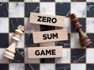 Two chess piece kings lying on the chessboard with the word zero sum game on a wooden block.