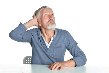 Portrait of senior man sitting at table on white background