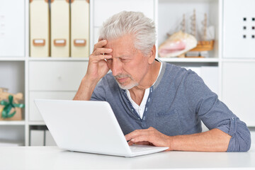 Portrait of emotional senior man using laptop