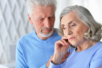 Sad beautiful senior couple posing at home
