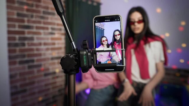 Girls dance on a smartphone camera. A view of the phone screen standing on a tripod. Social network. Blogger.