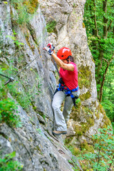 Fototapeta premium Frau bei einer Querung am steilen Fels im Klettersteig