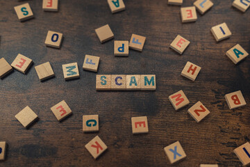 Obraz premium SCAM - a word put together with aligned wooden blocks with letters security and safety concept . High quality photo