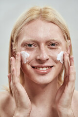 Portrait of guy smearing cosmetic cream on face