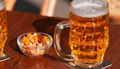 Two cold draught blonde beers and some peanuts on a table. Drinking on a pub terrace with friends. Drinks and beer photography.