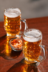 Two cold draught blonde beers and some peanuts on a table. Drinking on a pub terrace with friends. Drinks and beer photography.