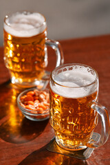 Two cold draught blonde beers and some peanuts on a table. Drinking on a pub terrace with friends. Drinks and beer photography.