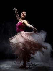 Fototapeta na wymiar Chica joven bailando en movimiento con polvos de harina en dispersión con fondo oscuro. Baile y danza artística. 