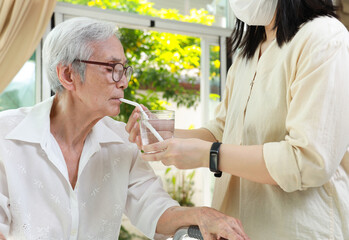 Asian caregiver take care of senior woman give drinking water from a glass,feeding water using a...
