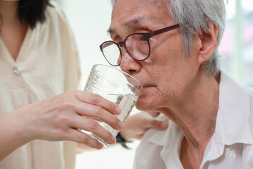 Nurse or caregiver gives drinking fresh water to senior woman in hospital or nursing home,Thirsty...