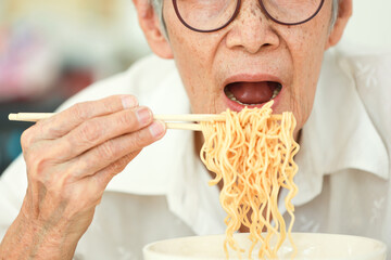 Close up,Asian senior woman opening her mouth to eat instant noodles,junk food,old elderly eating...