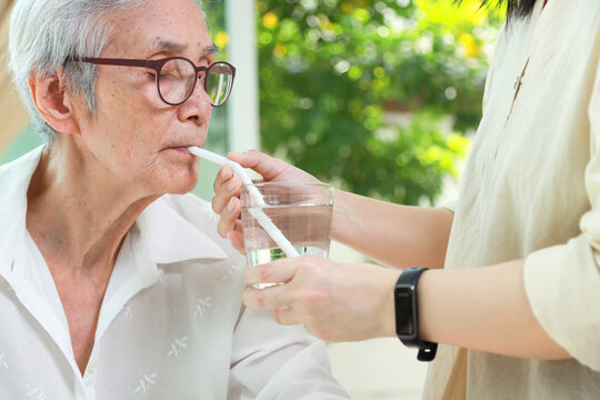 Thirsty asian senior woman drinking water with a straw,Do not use a straw to drink water prevent swallowing air causing flatulence in the elderly,concept of health care,lifestyle,food and beverage