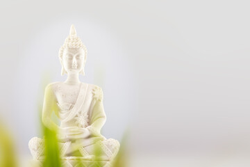 Buddhist composition with white Buddha statue on a neutral light gray background with copy space. Vesak, Buddha Day. Soft image and soft focus style. Mental health and meditation