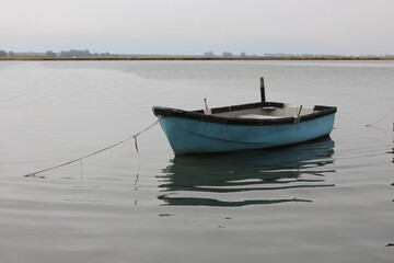 Naklejka na ściany i meble Old small blue fishing boat on water