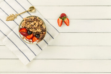 strawberry blueberry granola bowl on wooden white background