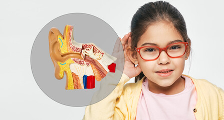 Hearing problems in children and treatment of deafness. Little girl holds hand near her ear for...