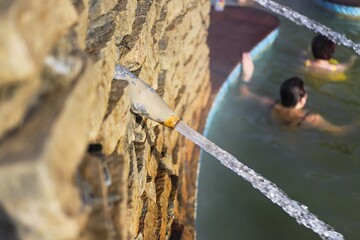 a jet of salt water beats out of stone and from underground at a spa resort in winter it is not cold