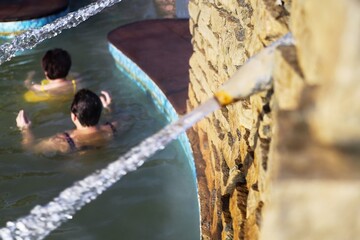 a jet of salt water beats out of stone and from underground at a spa resort in winter it is not cold