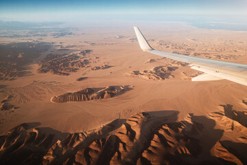 View from the plane on the wing and mountains in the desert of Africa